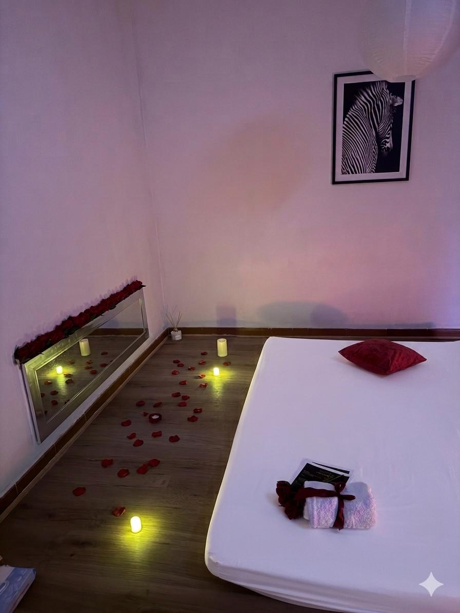 Sala de masaje erótico tántrico con pétalos de rosa, velas y ambiente romántico en Málaga
