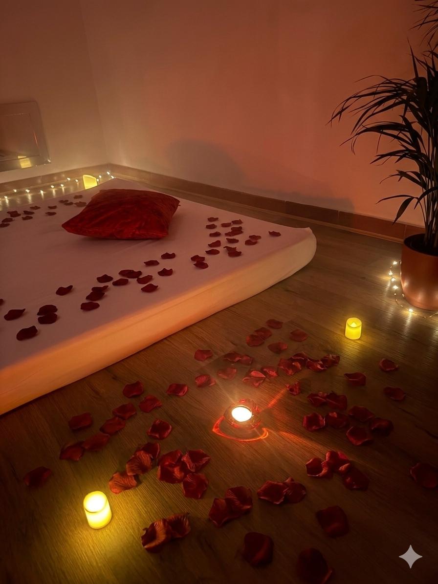 Sala de masaje erótico con pétalos de rosa, velas y luz dorada en centro tántrico Málaga